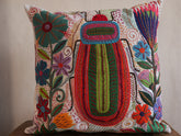 Coussin brode main avec des motifs insectes et fleur, commerce equitable.